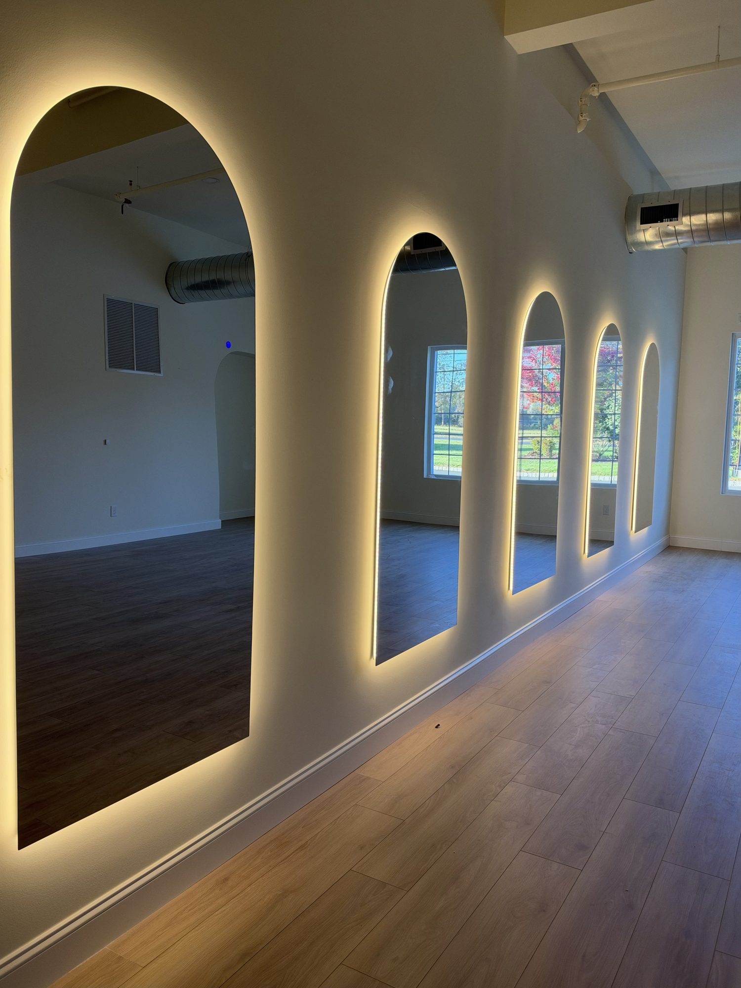Backlit arched mirrors along the wall of the LaVie Pilates studio
